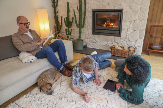 Mother and adult son reading in living room, father sitting on sofa - Powered by Adobe