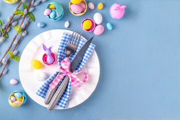 Spring Easter holiday menu table setting, cutlery and plate on pastel blue background with...