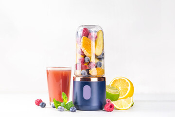 Healthy fruit and berry smoothie drink in portable portioned blender, Juicer Cup for smoothie, juice and shakes. Fruits in transparent blender cup and on table background, glass with fresh fruit shake