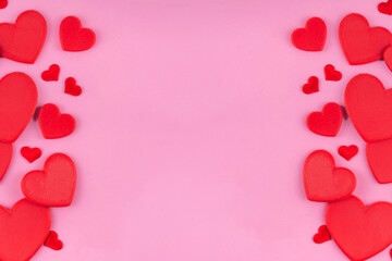 Valentine day pink background with red hearts, assorted red hearts layout simple pattern on pastel pink background, top view copy space. Valentine`s day invitation, menu, greeting card 