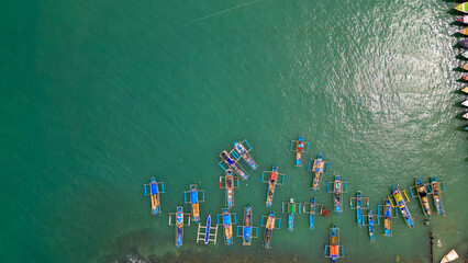A stunning view of Sadeng Beach Pier, where numerous fishing boats are docked, creating a lively...