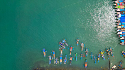 A stunning view of Sadeng Beach Pier, where numerous fishing boats are docked, creating a lively...