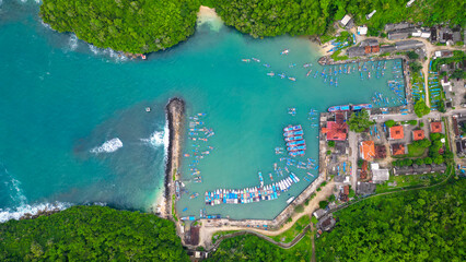 A breathtaking view of Sadeng Beach Pier, where dozens of fishing boats dock along the harbor,...