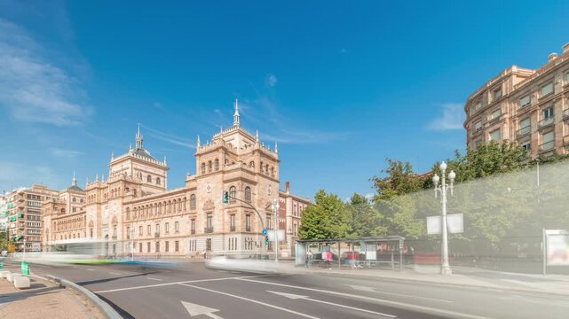 Panorama showing Cavalry Academy timelapse in Plaza de Zorrilla, Valladolid, Spain. Historic military building with intricate architecture, surrounded by busy urban scene under a blue sky with clouds
