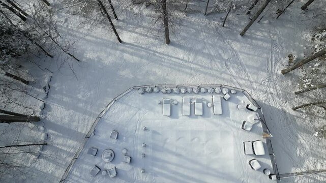 aerial view of snow covered lounge chairs next to closed shuttered swimming pool in winter (back yard patio loungers outdoor furniture) spa bizzard snowy snowfall frozen home countryside drone footage