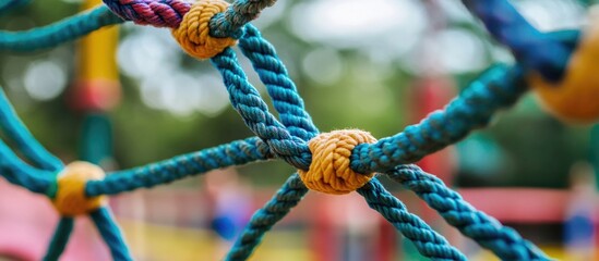 Colorful climbing rope netting in children's playground with blurred background, focus on knots and texture, Copy Space