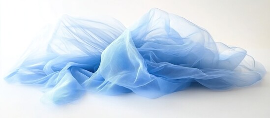 Obraz premium Soft translucent blue tulle fabric draped artistically with flowing folds and textures on a white background with Copy Space
