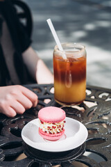 Girl with sweet pink macaroon dessert on cafe terrace on summer day.
