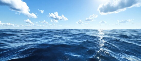 Fototapeta premium Panoramic view of clear blue ocean water with gentle waves under a bright sky with clouds and sunlight reflecting on the surface Copy Space