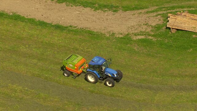 Vue a&eacute;rienne d'un tracteur bleu dans un champ fabriquant une botte de paille