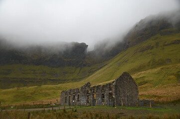 Ancient ruins beneath misty mountain landscape, serene. Ireland