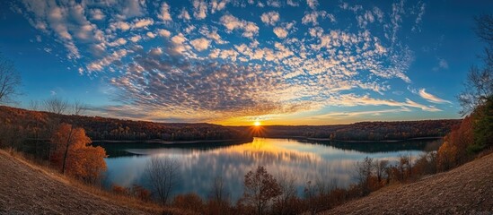 Panoramic view of a tranquil lake at sunset with vibrant skies and autumn foliage reflecting on the water Copy Space