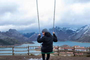 Tourist swinging over riano reservoir enjoying winter landscape, spain