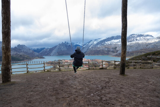 Tourist swinging over riano reservoir enjoying winter landscape, spain