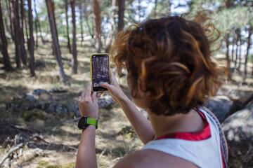 Woman hiking and taking pictures of forest with smartphone