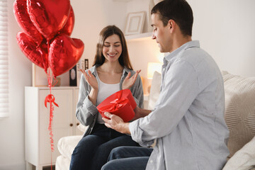 Lovely man surprising his girlfriend with Valentine's day gift indoors
