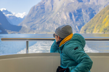Tourist enjoying milford sound scenic boat tour in fiordland national park, new zealand
