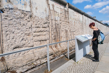 Tourist reading sign in front of berlin wall remains in germany