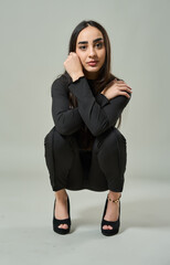 Confident woman crouching in black outfit