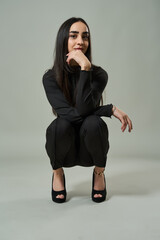 Confident woman crouching in black outfit