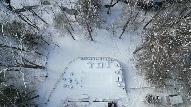 aerial view of snow covered lounge chairs next to closed shuttered swimming pool in winter (back yard patio loungers outdoor furniture) spa bizzard snowy snowfall frozen home countryside drone footage