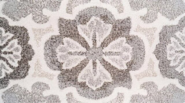 Rug with a floral design in white and gray. The rug is patterned with flowers and has a gray and white color scheme