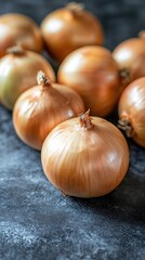 Group of Brown Onions on Dark Textured Surface in Close Up Still Life Food Photography