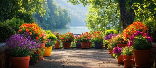 Lush garden terrace filled with colorful flower pots overlooking a serene lake and trees for a tranquil outdoor scene with Copy Space