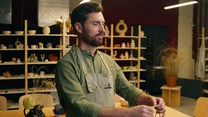 Caucasian happy smiling salesman potter male man guy businessman artist small business owner sculptor selling pottery vase ceramic give shopping bag to customer getting money dollars in store workshop