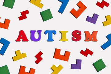 Word Autism with colorful wooden puzzles on white background. Autism Acceptance Month. Autism concept