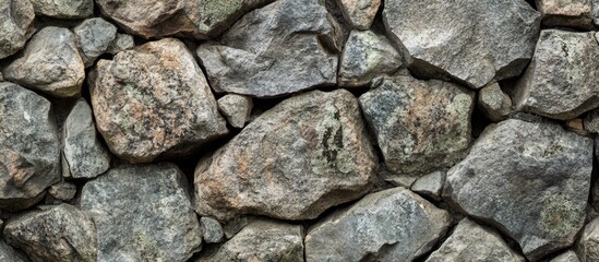 Fototapeta premium Textured gray stone wall background with varied rock sizes and shapes natural surface suitable for backgrounds and texture design Copy Space