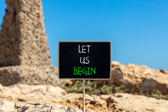Let us begin symbol. Concept words Let us begin on beautiful black yellow blackboard. Beautiful stone and blue sky background. Business motivational let us begin concept. Copy space.