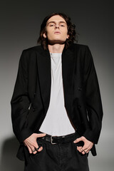 A stylish young man exudes confidence in a chic black blazer and minimalist outfit.