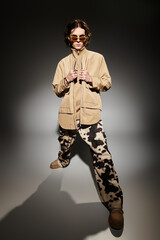 Trendy young man showcases his unique fashion sense with an elegant pose in a studio setting.