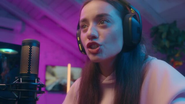 Happy Caucasian girl woman winner playing virtual game computer speaking microphone influencer female gamer winning match cyber sport gold champion receive cup addict streamer celebrate at home neon