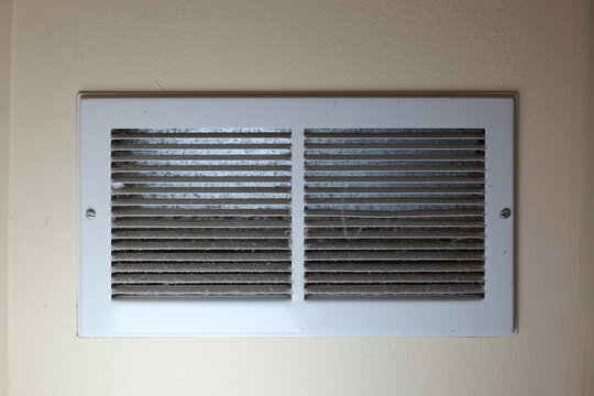 close-up of dusty louvered air white return air grille vent cover powder coated steel for ventilation system dirty needs cleaning abstract background