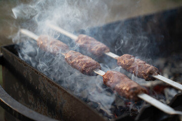 Food cooked outdoors on charcoal, hands in frame. Barbecue.