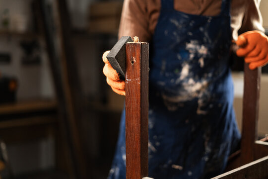 Close-up of man sanding old wooden chair with sponge. furniture renovation, diy and improvement