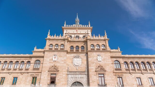 Timelapse of the Cavalry Academy facade in Plaza de Zorrilla, Valladolid, Spain. Historic military building with intricate architecture, surrounded by a busy urban scene under a blue sky with clouds.