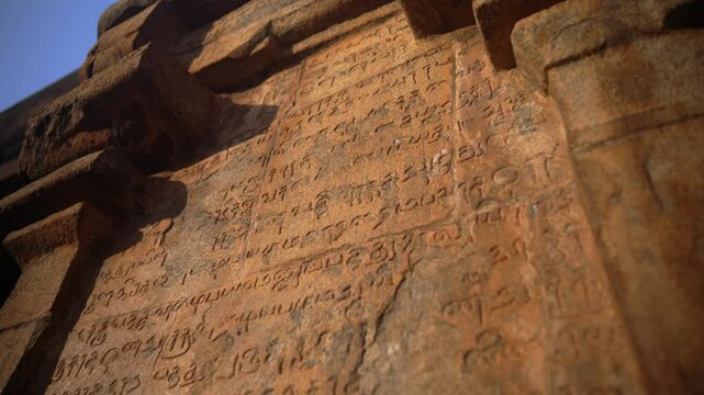 Close-up footage of ancient inscriptions carved into the stone walls of a historic temple in Thanjavur, South India.