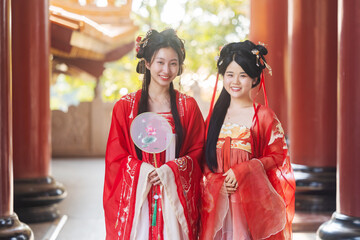 Asian women in traditional Chinese red attire holding a parasol for Chinese New Year