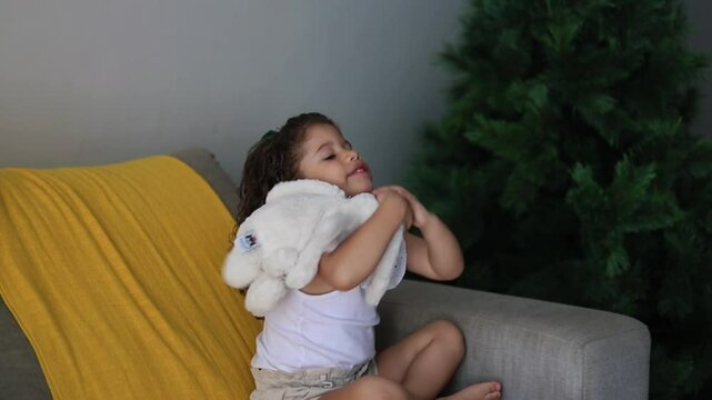 menina brincando na sala de casa com urso de pel&uacute;cia