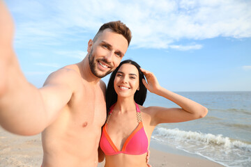 Fototapeta premium Happy young couple taking selfie on beach