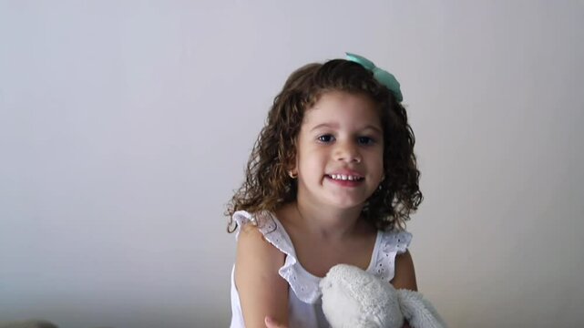 menina olhando para c&acirc;mera com um urso de pel&uacute;cia 