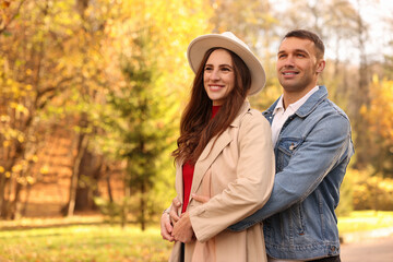 Fototapeta premium Happy couple spending time together in autumn park, space for text