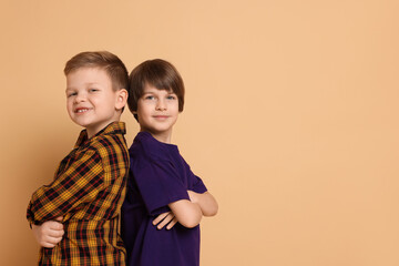 Portrait of cute brothers on beige background. Space for text