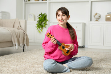 Happy woman playing ukulele on floor at home