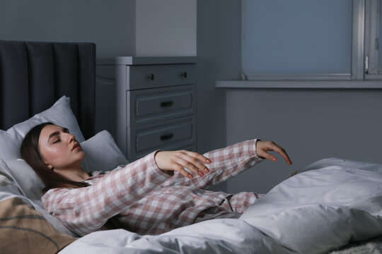 Young woman suffering from sleepwalking on bed at home