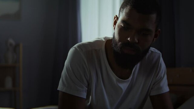Bearded black man leans onto fist feeling insecure at home