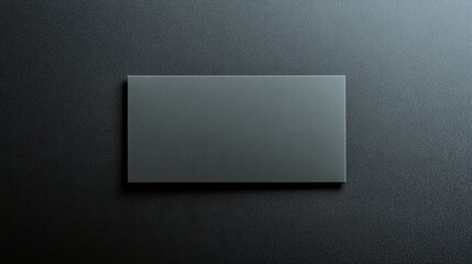 Blank grey rectangular card rests on a solid black background in a minimalistic setting